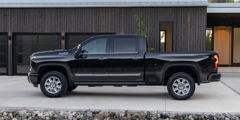 Black Chevrolet Silverado HD Lateral view parked next to a modern house